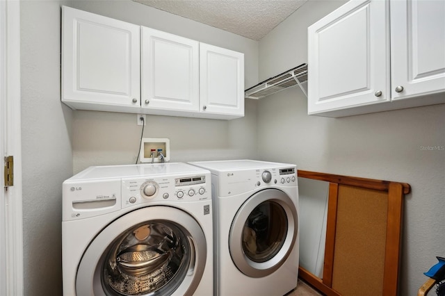 laundry area featuring separate washer and dryer, a textured ceiling, and cabinet space