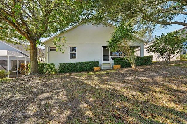 rear view of house featuring glass enclosure and stucco siding