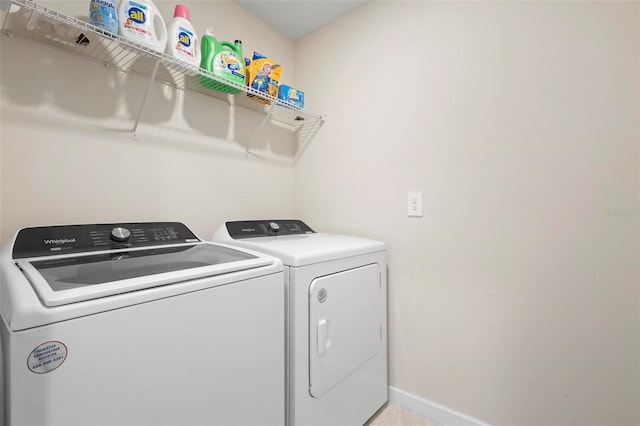 washroom featuring washer and dryer, laundry area, and baseboards