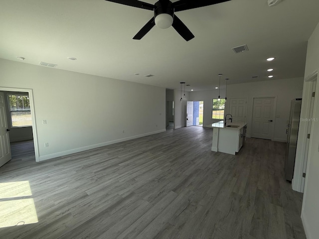 unfurnished living room with baseboards, visible vents, a sink, and light wood-style floors