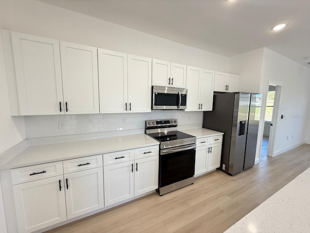 kitchen featuring backsplash, stainless steel appliances, white cabinets, and light wood finished floors