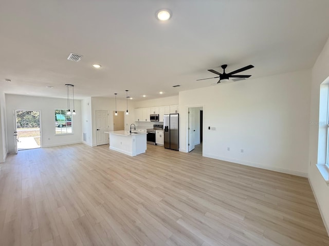 unfurnished living room featuring a sink, recessed lighting, baseboards, a ceiling fan, and visible vents