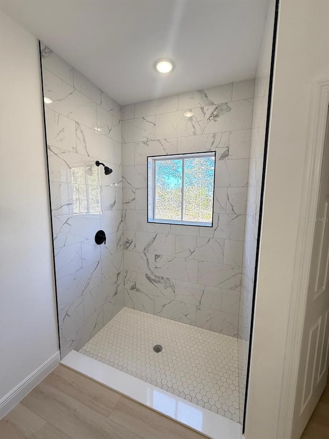 full bath with a tile shower and wood finished floors