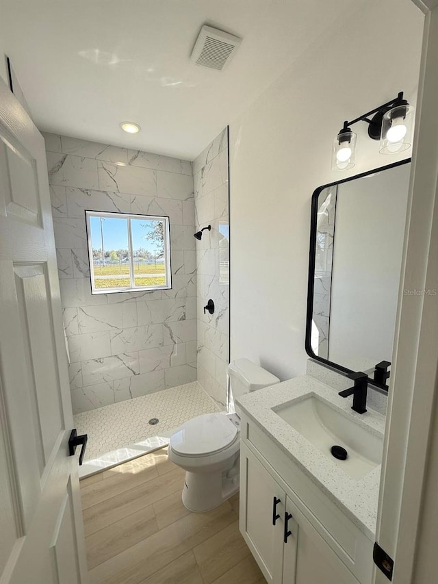 full bathroom featuring visible vents, vanity, wood finished floors, toilet, and a stall shower