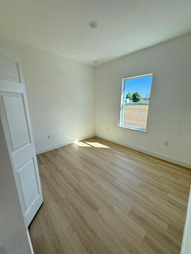 spare room with baseboards and light wood-style floors