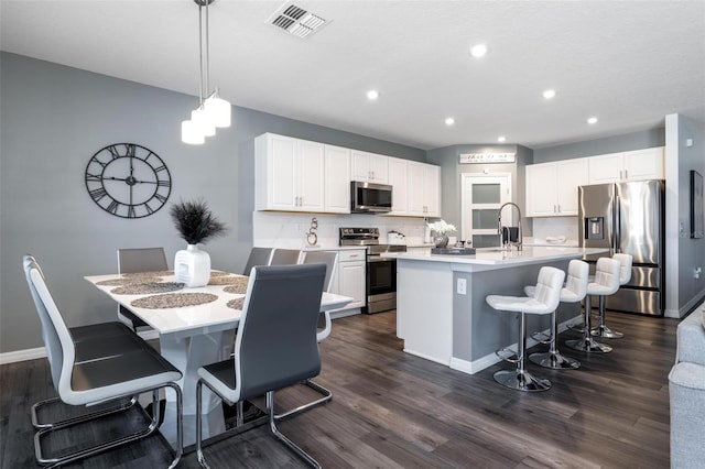 555 Meadow Bend Dr, Davenport, FL 33837 - kitchen featuring stainless steel appliances, a kitchen breakfast bar, white cabinetry, dark wood-style flooring, and recessed lighting