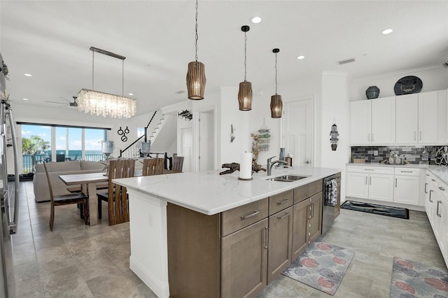 7 Marden Dr, Ormond Beach, FL 32176 - kitchen featuring a sink, decorative backsplash, a center island with sink, white cabinets, and hanging light fixtures