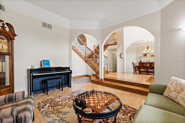 living area featuring visible vents, an inviting chandelier, baseboards, stairway, and arched walkways