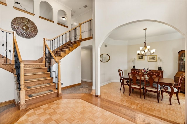 dining room featuring stairway, arched walkways, baseboards, and a chandelier