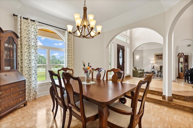 dining space featuring baseboards, arched walkways, and a notable chandelier