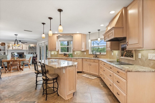 kitchen with a kitchen breakfast bar, backsplash, light brown cabinetry, light stone countertops, and black electric cooktop