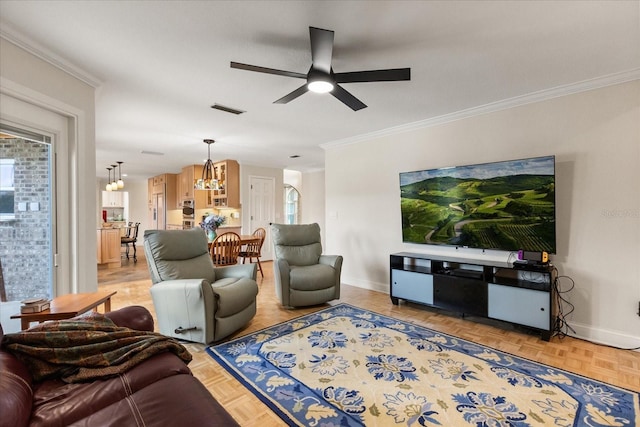 living room featuring crown molding, baseboards, ceiling fan with notable chandelier, and visible vents
