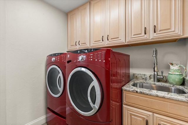 laundry room featuring cabinet space, baseboards, a sink, and washer and clothes dryer