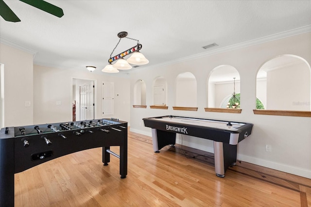 recreation room featuring crown molding, baseboards, visible vents, and light wood-type flooring