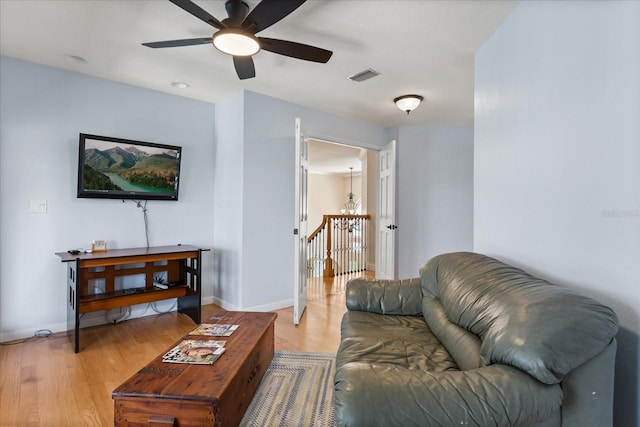 living room featuring visible vents, a ceiling fan, baseboards, and wood finished floors