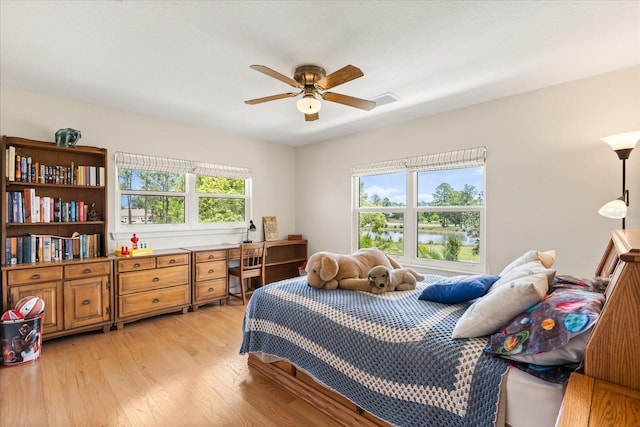 bedroom with light wood-style floors, a ceiling fan, and visible vents