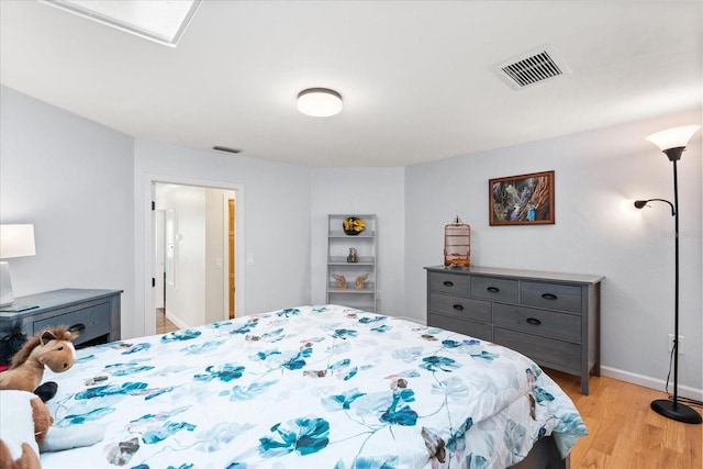 bedroom featuring baseboards, light wood finished floors, and visible vents