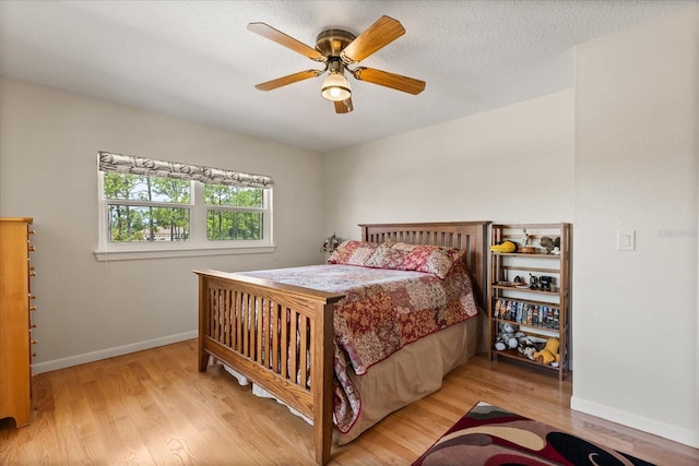 bedroom with a ceiling fan, baseboards, and wood finished floors
