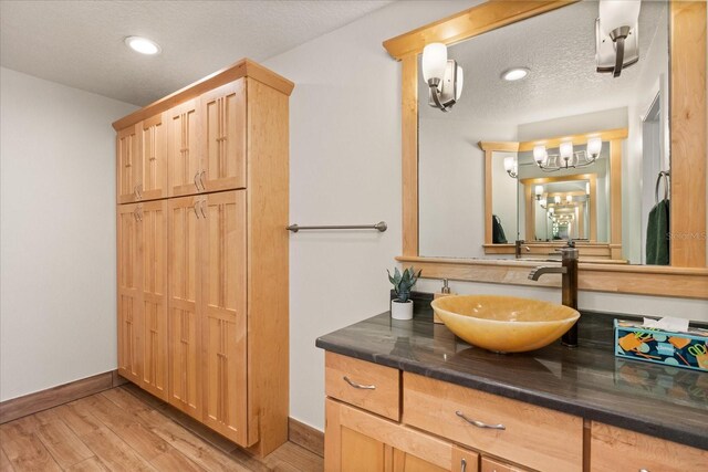 bathroom with vanity, a textured ceiling, baseboards, and wood finished floors