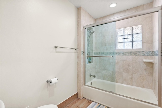 bathroom with toilet, baseboards, enclosed tub / shower combo, and wood finished floors