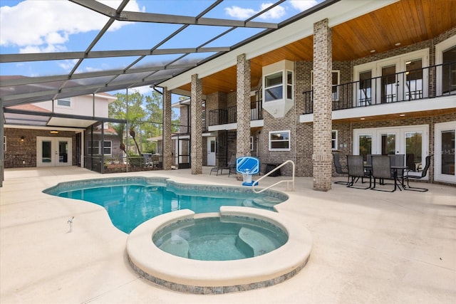 view of swimming pool with french doors, a lanai, a pool with connected hot tub, and a patio area