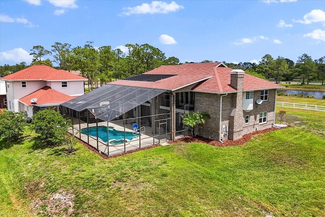 rear view of house with an outdoor pool, a patio area, glass enclosure, a yard, and a water view
