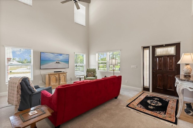 carpeted living room with baseboards, a towering ceiling, and a healthy amount of sunlight