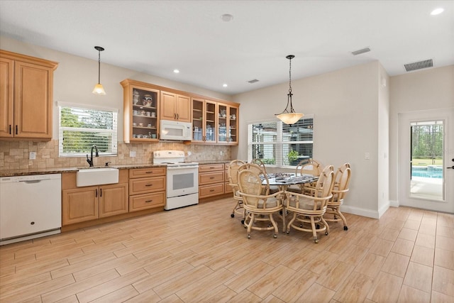kitchen with white appliances, backsplash, plenty of natural light, and a sink