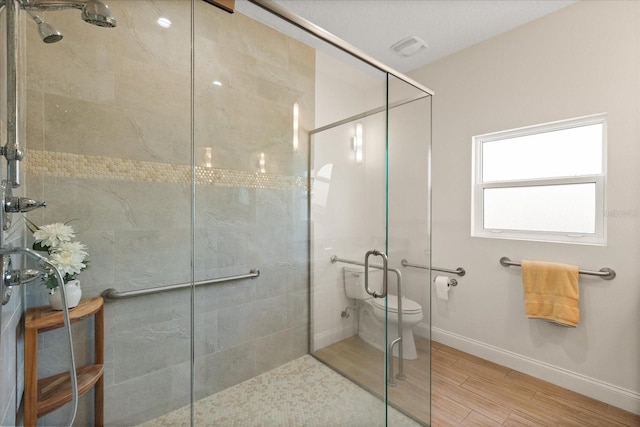 bathroom with baseboards, wood finished floors, toilet, and a shower stall