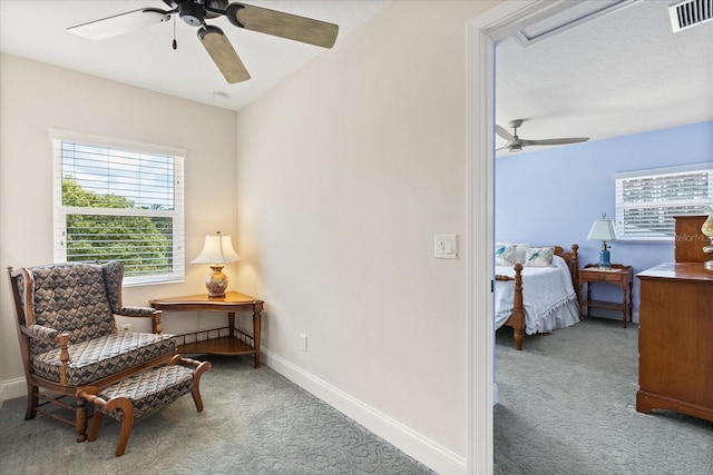 sitting room with visible vents, carpet floors, a wealth of natural light, and ceiling fan