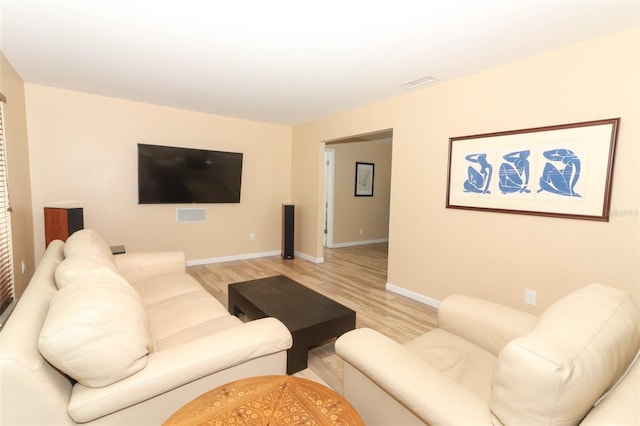 living room featuring light wood-style floors, baseboards, and visible vents