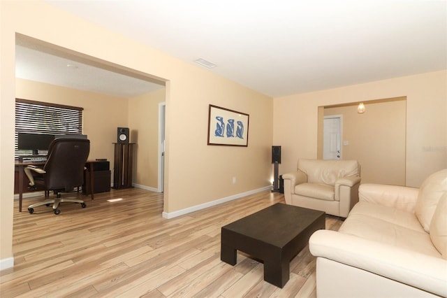 living area featuring baseboards, light wood-style flooring, and visible vents