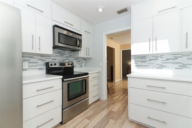 kitchen featuring visible vents, light countertops, tasteful backsplash, light wood-style flooring, and appliances with stainless steel finishes