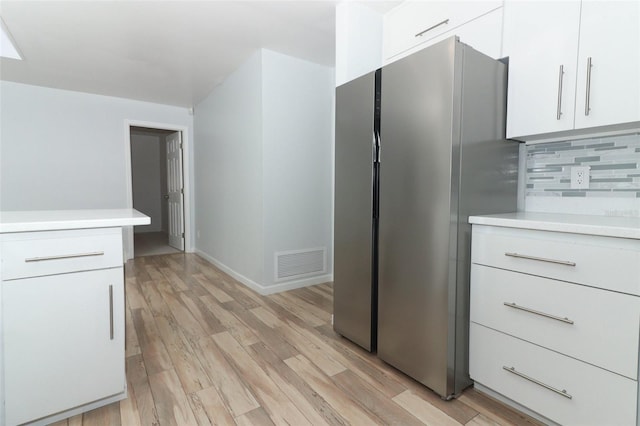 kitchen with visible vents, freestanding refrigerator, white cabinetry, and light countertops
