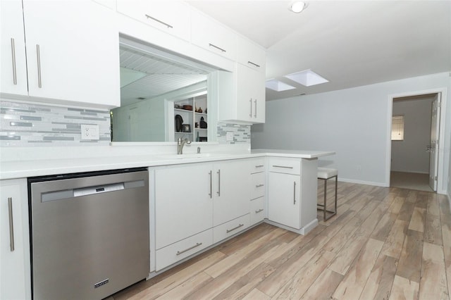 kitchen featuring stainless steel dishwasher, white cabinets, decorative backsplash, and light countertops
