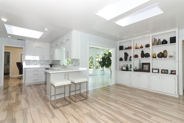 kitchen with a skylight, light countertops, light wood-type flooring, and a sink