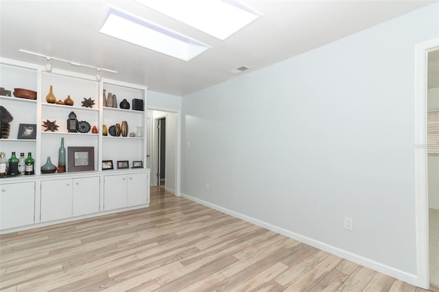 spare room with light wood-type flooring, rail lighting, baseboards, and visible vents