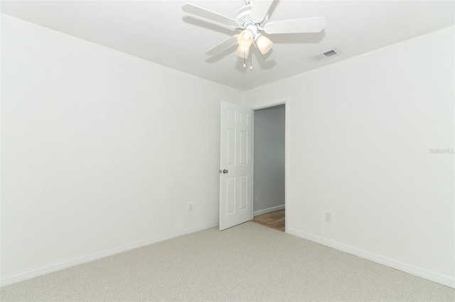 empty room featuring baseboards, a ceiling fan, visible vents, and light carpet