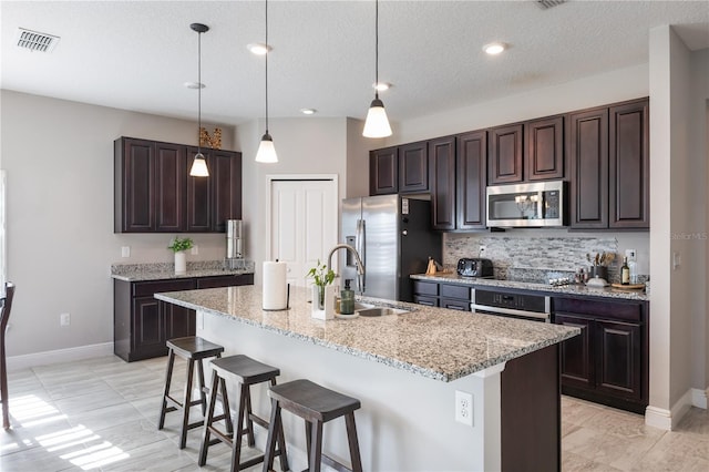kitchen with a sink, appliances with stainless steel finishes, a kitchen breakfast bar, and dark brown cabinets