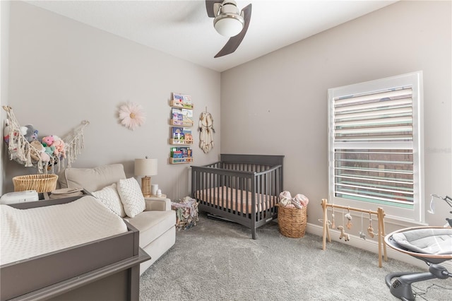 carpeted bedroom featuring baseboards, ceiling fan, and a nursery area