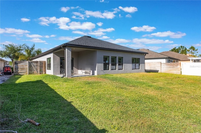 back of house with a lawn, a patio area, stucco siding, and fence