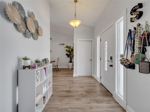 foyer entrance featuring baseboards, light wood-style flooring, lofted ceiling, and a wealth of natural light