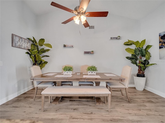 dining room with baseboards, wood finished floors, visible vents, and vaulted ceiling
