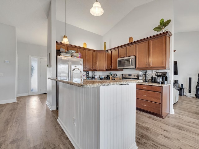 kitchen with light wood-style floors, high vaulted ceiling, hanging light fixtures, and stainless steel appliances