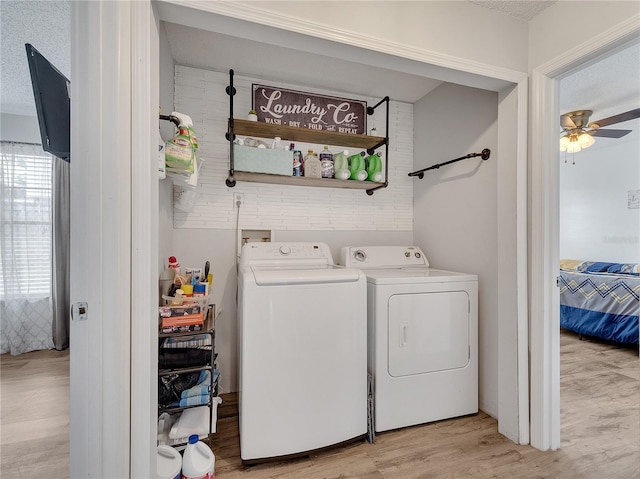 laundry area with laundry area, a ceiling fan, light wood-type flooring, and washer and dryer