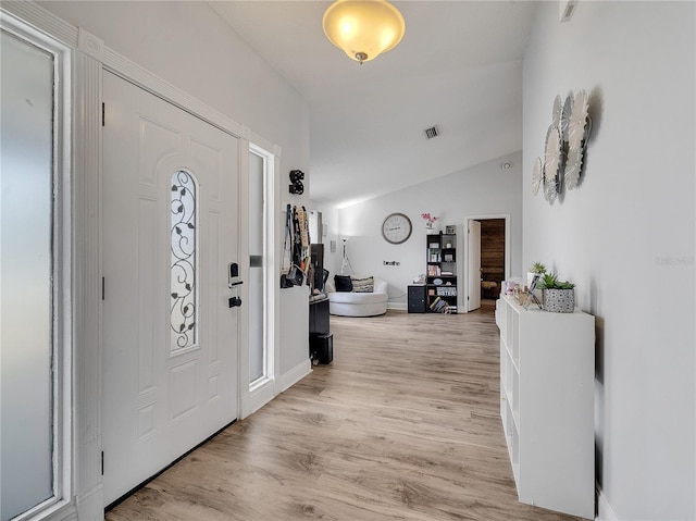 entrance foyer with baseboards, lofted ceiling, light wood-style flooring, and visible vents