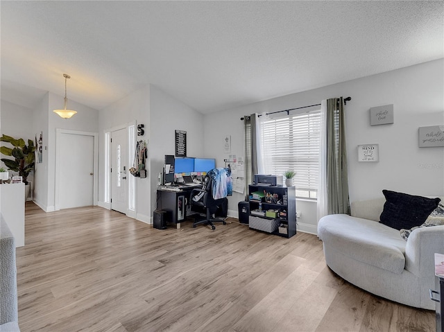 living area featuring baseboards, lofted ceiling, and light wood finished floors
