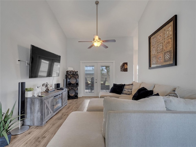 living room with high vaulted ceiling, ceiling fan, french doors, and light wood-style flooring