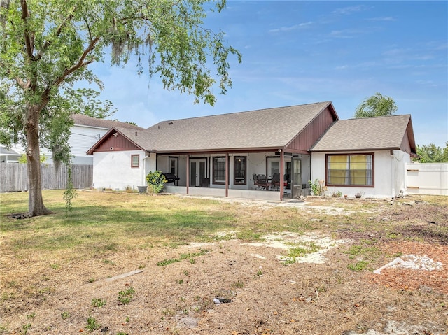 back of property featuring a lawn, a shingled roof, fence, and a sunroom
