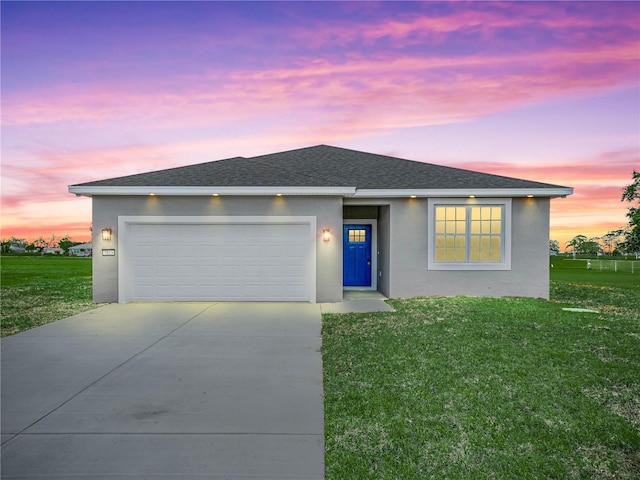ranch-style home with a yard, an attached garage, stucco siding, and driveway